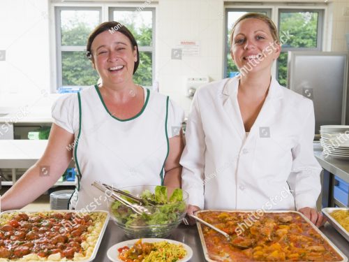 stock-photo-two-lunch-ladies-standing-behind-full-lunch-service-station-76861825